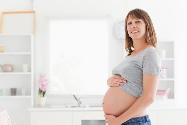 Linda mulher grávida posando enquanto acaricia sua barriga — Fotografia de Stock