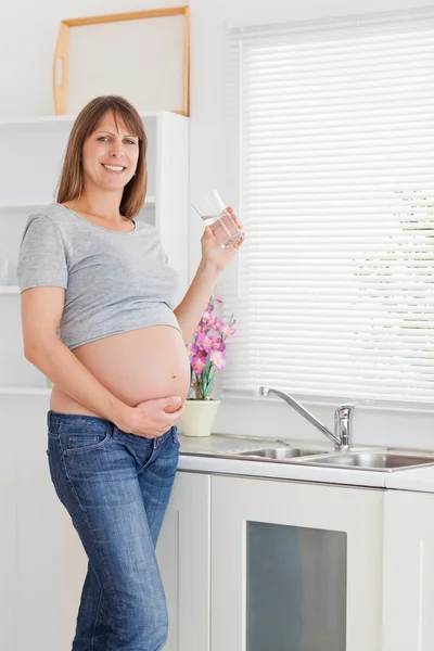 Mulher muito grávida bebendo um copo de água em pé — Fotografia de Stock