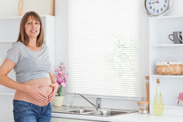 Linda fêmea grávida posando enquanto acaricia sua barriga — Fotografia de Stock