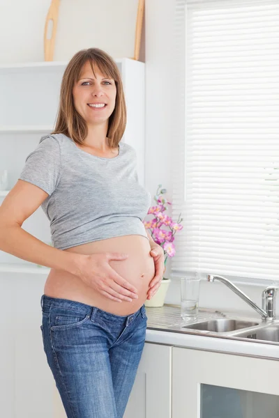 Atrakcyjna kobieta ciąży pozowanie podczas pieszczot jej brzuch — Zdjęcie stockowe