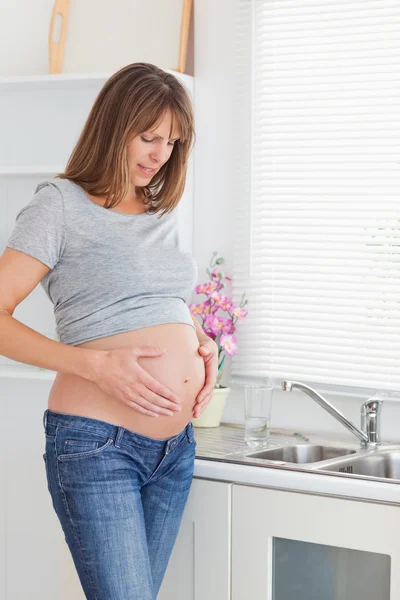 Όμορφη έγκυος γυναίκα που παρουσιάζουν ενώ χαϊδεύει την κοιλιά — Φωτογραφία Αρχείου