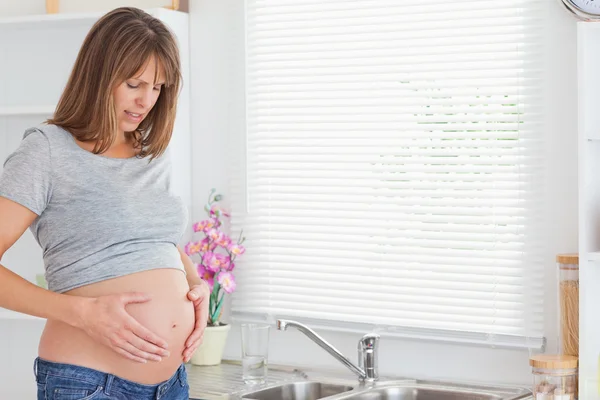Красивая беременная женщина позирует, лаская живот. — стоковое фото