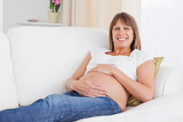 Iyi görünümlü hamile kadın kanepede yatan ise poz — Stok fotoğraf