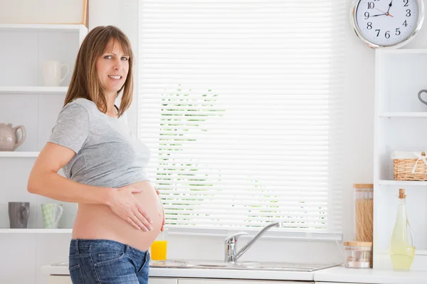 Όμορφη έγκυο γυναίκα που χαϊδεύει την κοιλιά, ενώ στέκεται — Φωτογραφία Αρχείου