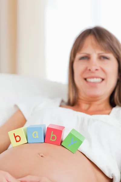 Bella donna incinta che gioca con blocchi di legno mentre lyi — Foto Stock