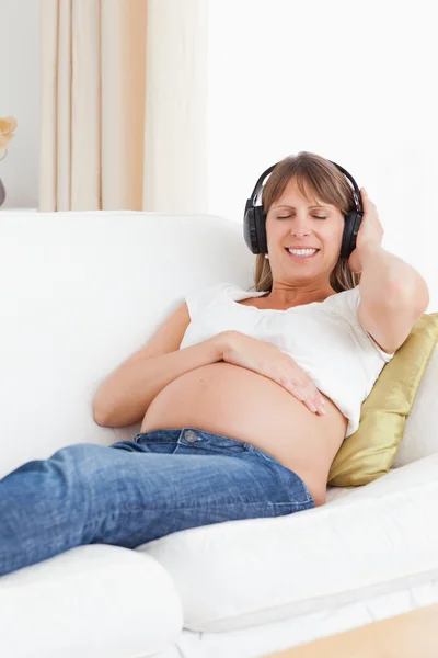 Portrait of a pregnant woman listening to music — Stockfoto
