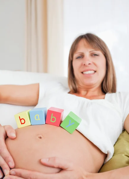 Good looking pregnant female playing with wooden blocks while ly — Stockfoto