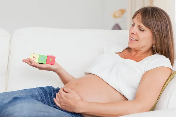 Aantrekkelijke zwangere vrouw spelen met houten blokken en gelet — Stockfoto