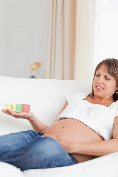Gut aussehende schwangere Frau spielt mit Holzklötzen und havin — Stockfoto