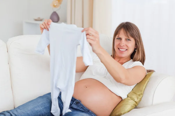 Γοητευτική έγκυος γυναίκα, κρατώντας ένα μωρό αυξάνεται ενώ βρίσκεται σε μια sof — Φωτογραφία Αρχείου