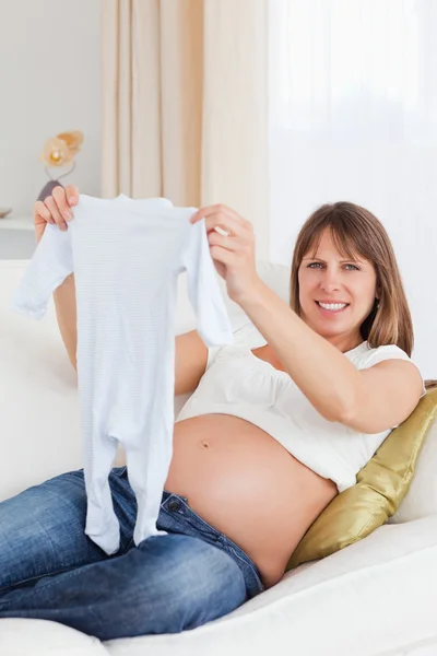 Wunderschöne schwangere Frau hält ein Baby wachsen, während sie auf einem sof liegt — Stockfoto