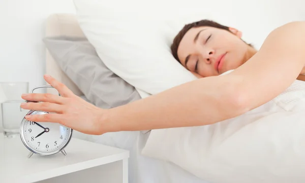 Close up of a cute brunette turning off her alarm clock — Stock Photo, Image