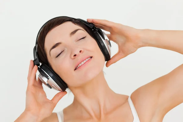 Gros plan d'une brune enchantée écoutant de la musique — Photo