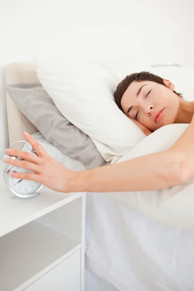 Portrait of a brunette turning off her alarm clock — Stock Photo, Image