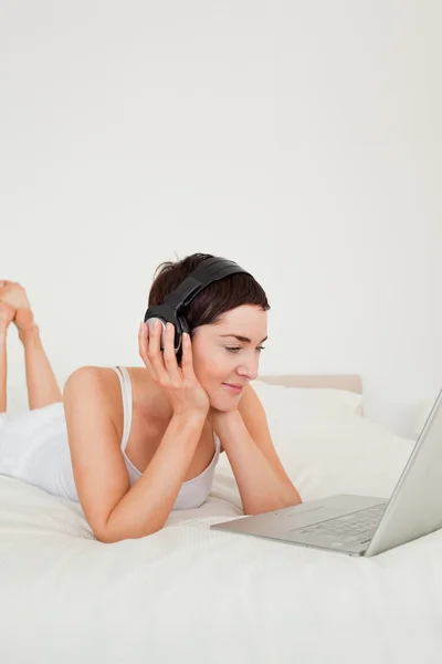 Porträtt av en ung kvinna som lyssnar på musik med sin laptop — Stockfoto