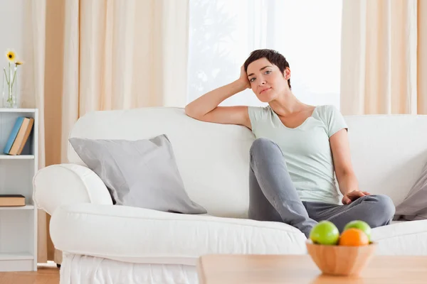 Leende kvinna sitter på en soffa — Stockfoto