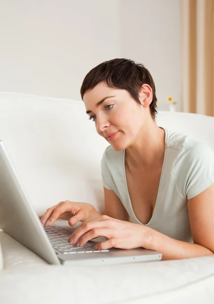 Πορτρέτο του ένα πανέμορφο κοντά μαλλιά γυναίκα χρησιμοποιώντας ένα φορητό υπολογιστή — Φωτογραφία Αρχείου