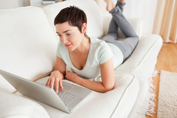 Bájos sötét hajú nő használ egy laptop — Stock Fotó