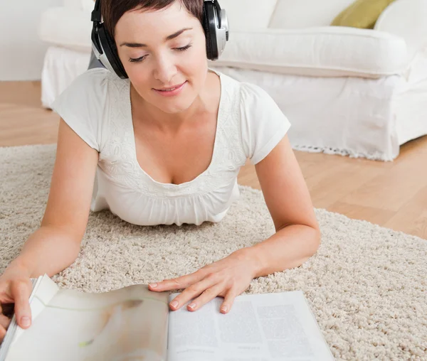 En kvinne som leser et blad og nyter litt musikk – stockfoto