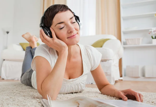 Glad kvinna med en tidning som njuter av lite musik — Stockfoto