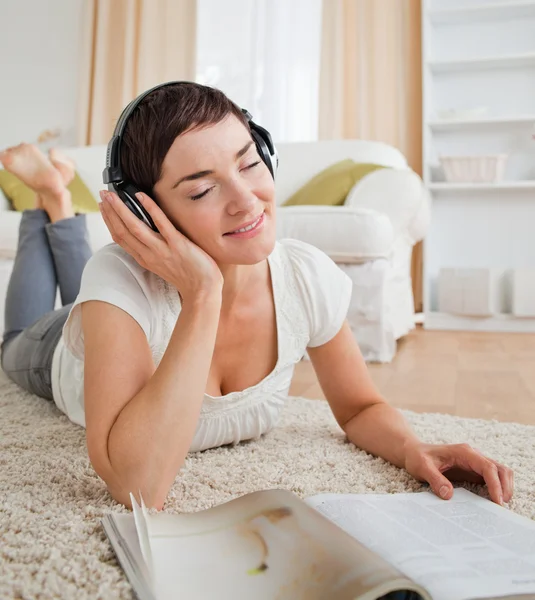 Portrait of a delighted woman with a magazine enjoying some musi — Stock Photo, Image