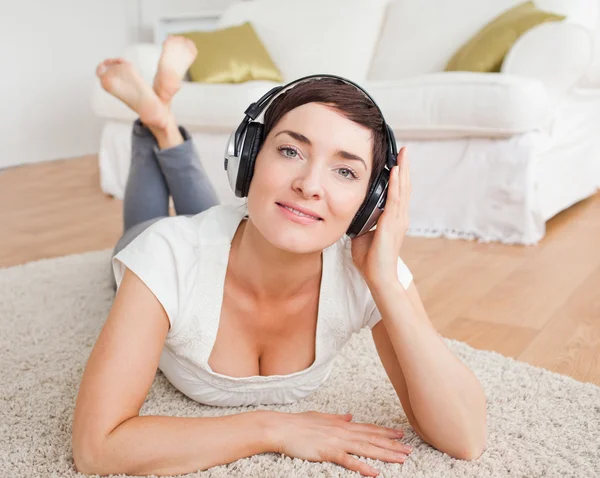 Närbild av en leende brunett som lyssnar på musik — Stockfoto