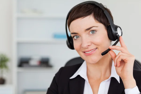 Fechar de uma secretária sorrindo chamando com um fone de ouvido — Fotografia de Stock