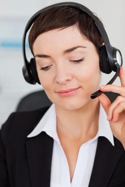 Retrato de uma secretária sorrindo chamando com um fone de ouvido — Fotografia de Stock