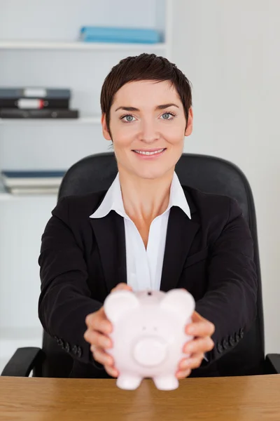 Porträt einer lächelnden Büroangestellten mit einem Sparschwein — Stockfoto