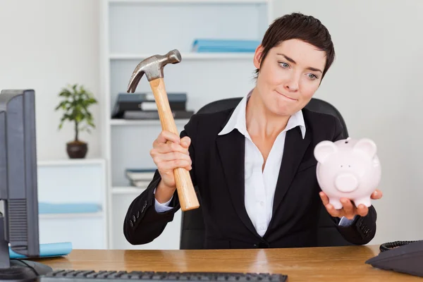 Office worker breaking a piggybank with a hammer — Stock Photo, Image