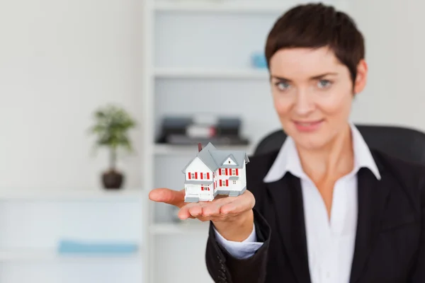 Brunette showing a house miniature — Stock Photo, Image