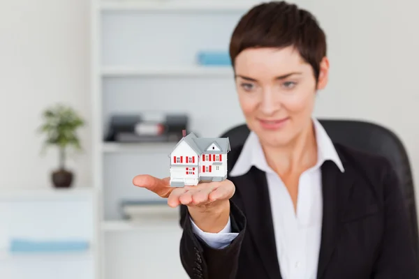 Young brunette showing a house miniature — Stock Photo, Image