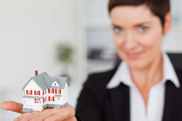 Close up of a brunette showing a house miniature — Stock Photo, Image