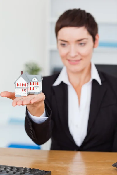 Portrait of a businesswoman showing a miniature house — Stock Photo, Image