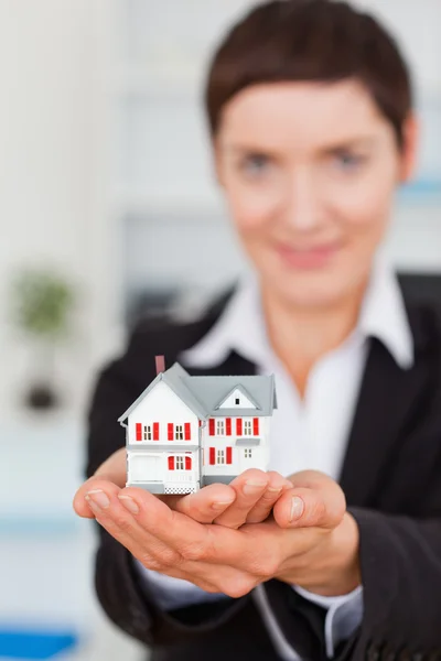 Portrait of a businesswoman holding a miniature house — Stock Photo, Image