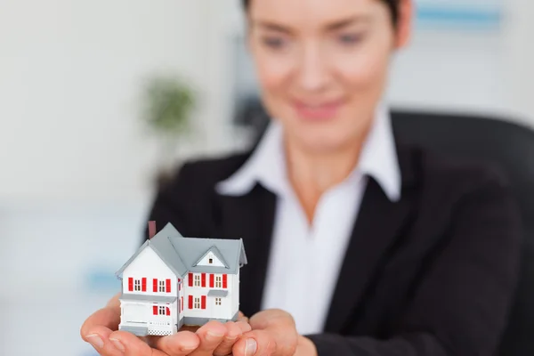 Leende affärskvinna innehar en miniatyr hus — Stockfoto