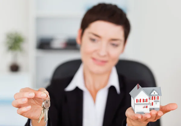 Empresária mostrando uma casa em miniatura e uma chave — Fotografia de Stock