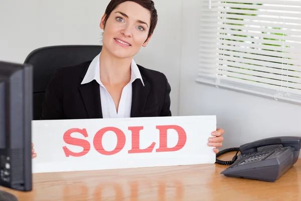 Sorrindo agente imobiliário com um painel vendido — Fotografia de Stock
