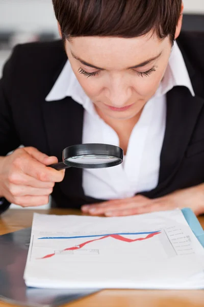Geschäftsfrau schaut mit der Lupe auf ein Diagramm — Stockfoto