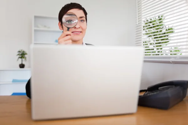 Businesswoman looking through a magnifying glass — Stock Photo, Image