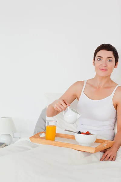 Portrait of a woman pouring milk into her cereal — Stock Photo, Image