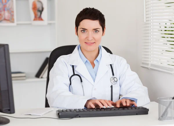Kvinnliga läkare att skriva med hennes dator — Stockfoto