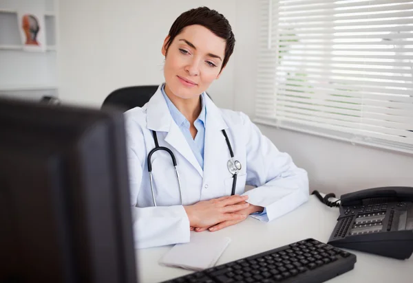 Серьёзная женщина-врач смотрит в свой компьютер — стоковое фото