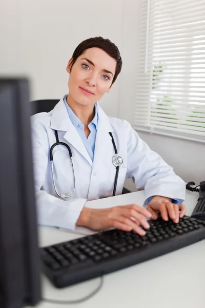 Portret lekarza kobieta uśmiechający się pisząc na maszynie z jej komputera — Zdjęcie stockowe