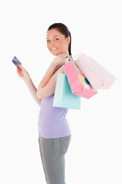 Hermosa mujer con una tarjeta de crédito sosteniendo bolsas de compras mientras s — Foto de Stock