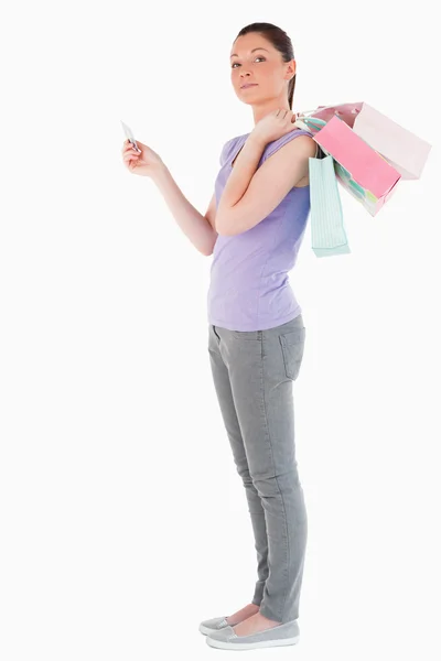 Mulher bonita com um cartão de crédito segurando sacos de compras enquanto — Fotografia de Stock