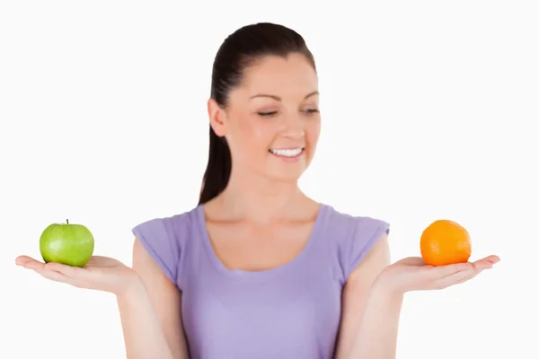 Portrait of an attractive woman holding fruits while standing — Stock Photo, Image