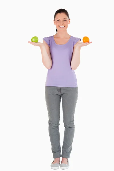 Mulher bonita segurando frutas enquanto está de pé — Fotografia de Stock