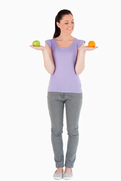 Mujer guapa sosteniendo frutas mientras está de pie — Foto de Stock