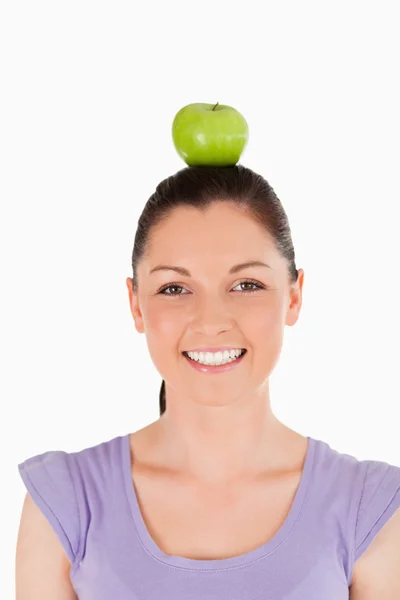 Portrait of an attractive woman holding an apple on her head whi — Stock Photo, Image